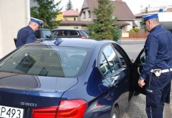 Policjanci Wydziału Ruchu Drogowego na parkingu komendy wsiadają do radiowozu nieoznakowanego BMW